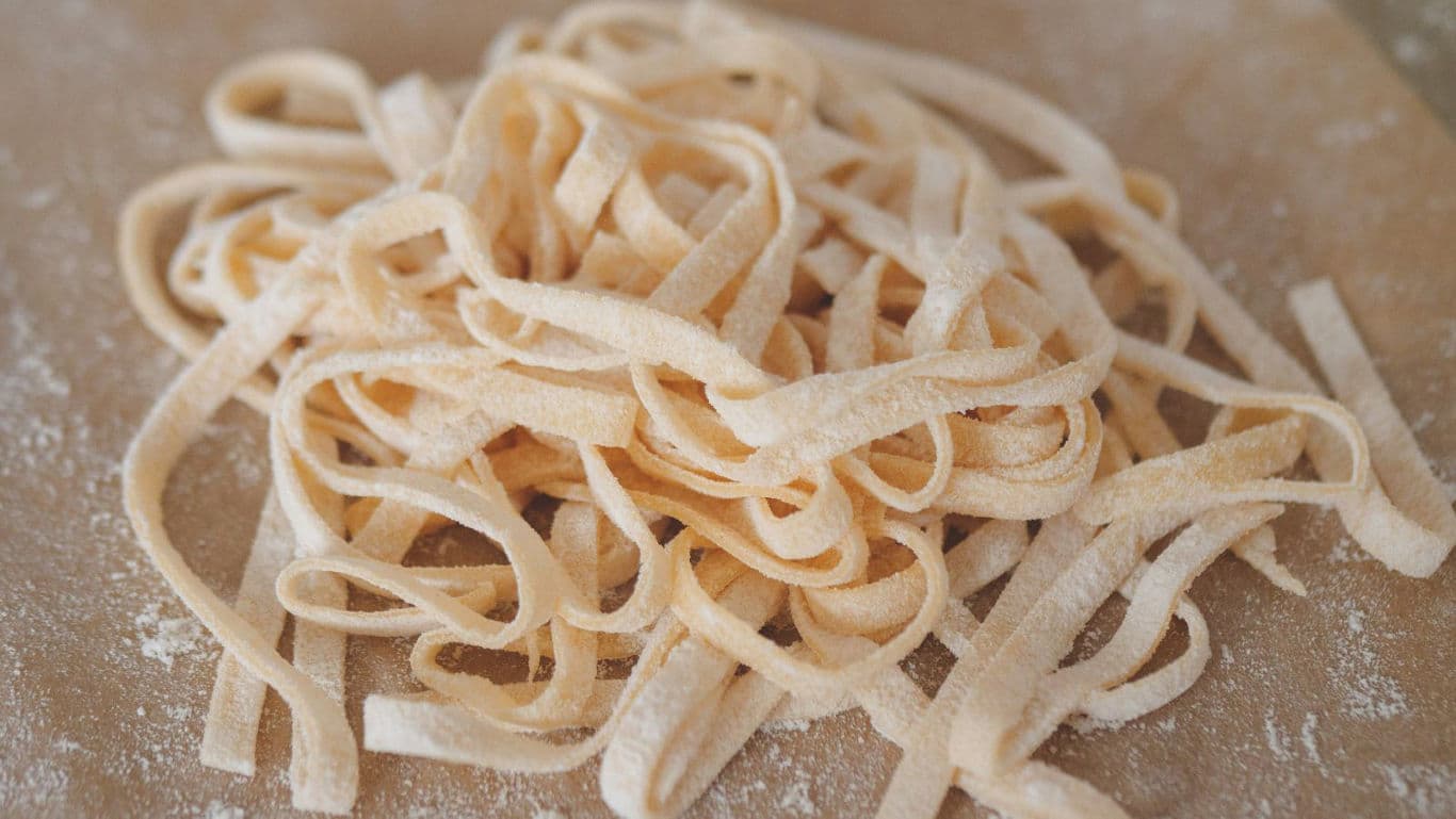 Fresh homemade pasta noodles on floured board