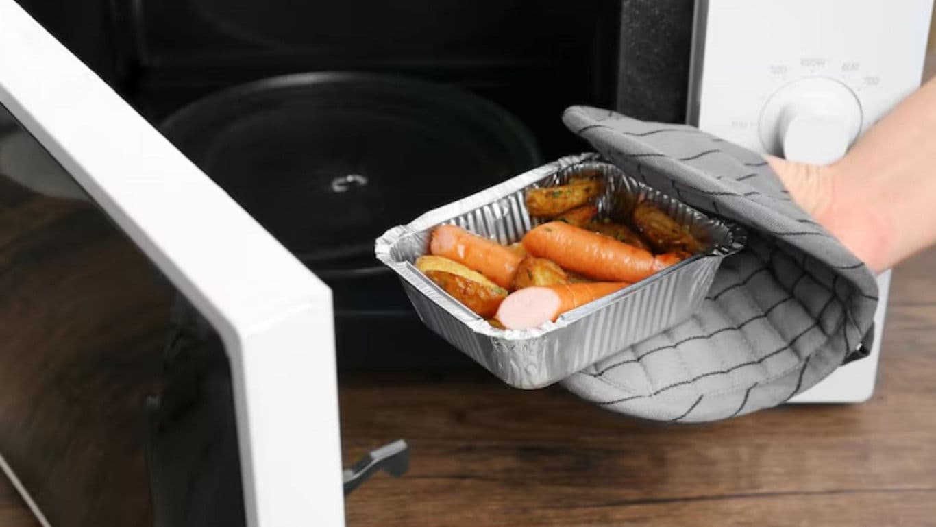 Hand removing food tray from microwave