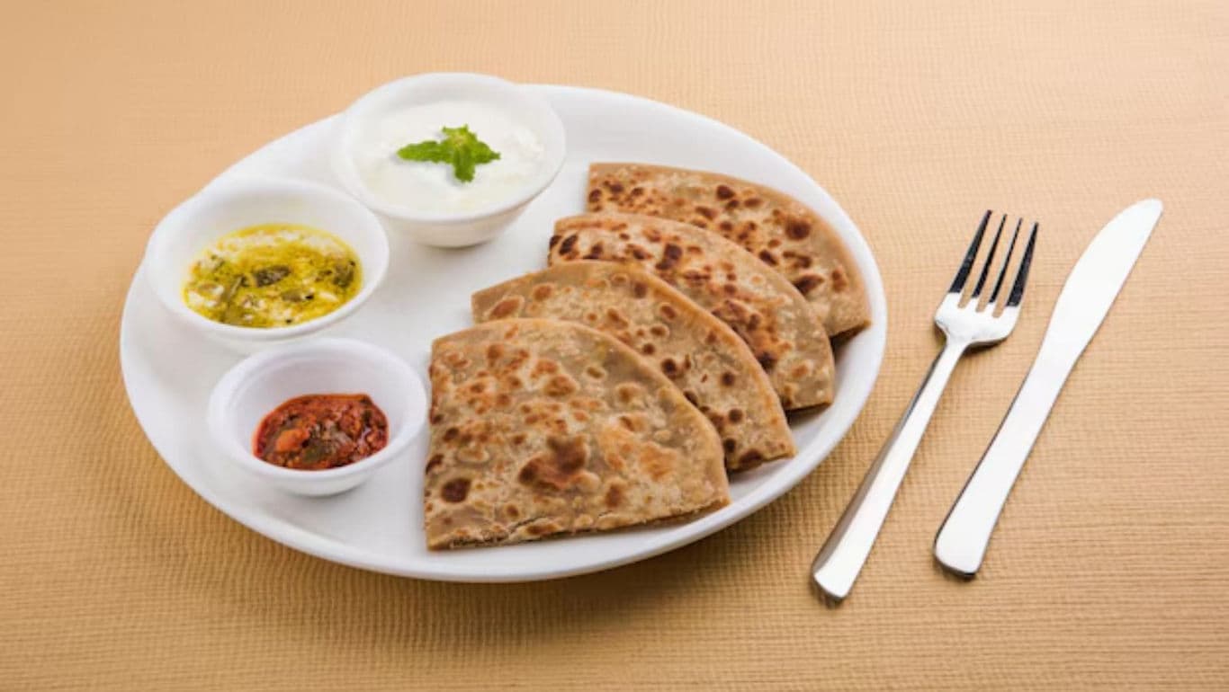 Indian stuffed paratha with yogurt and pickles on plate