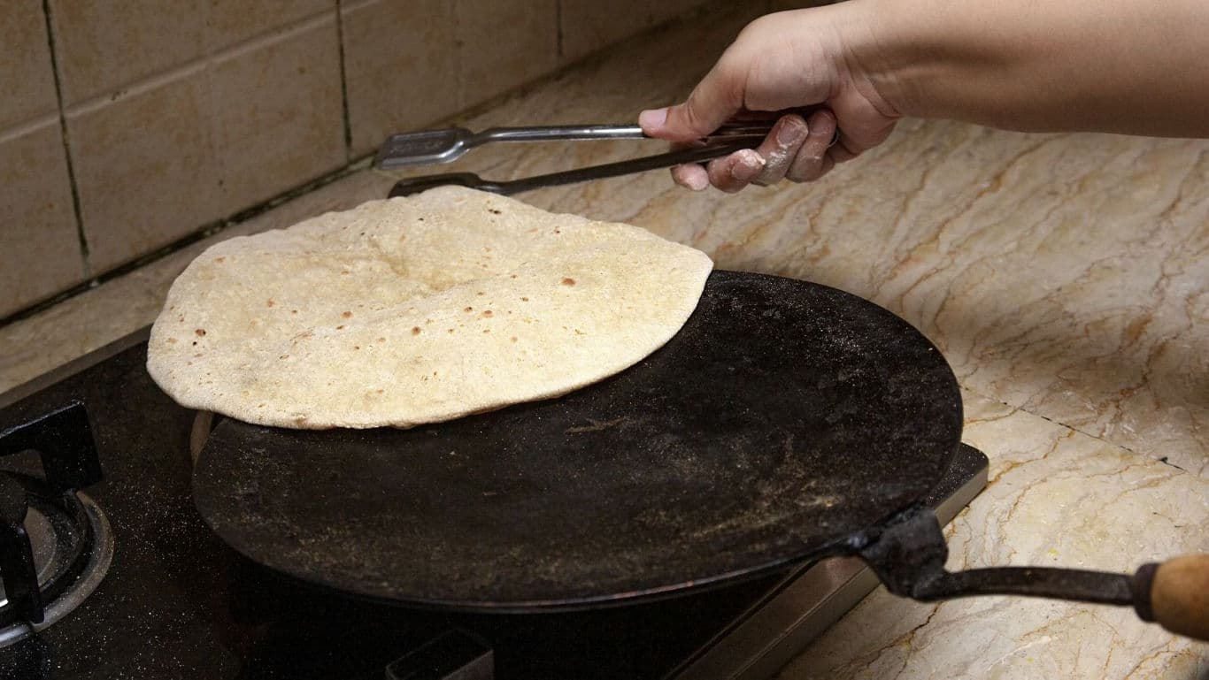 Hand cooking flatbread on stovetop griddle
