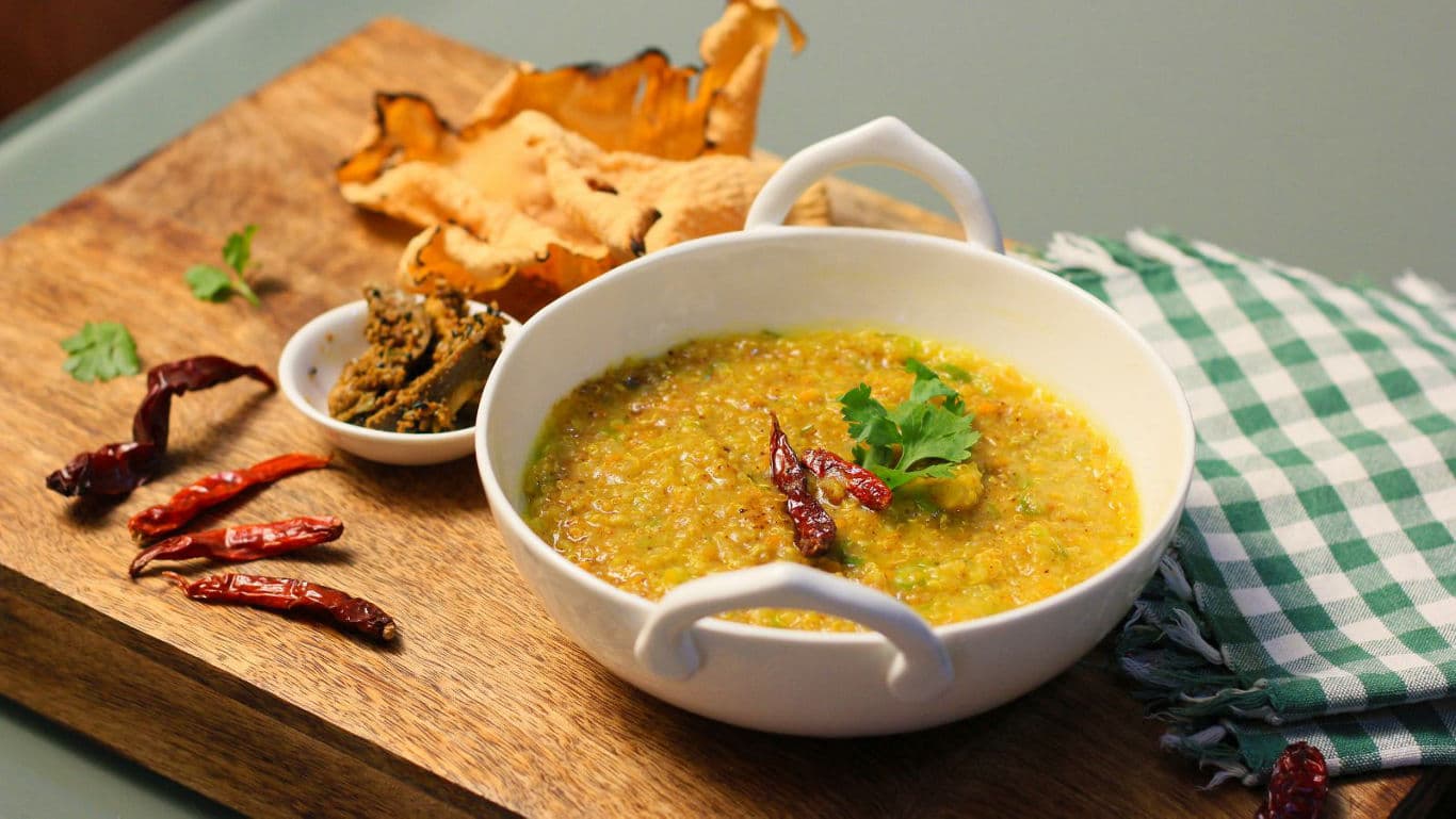 Spicy lentil curry with sides on wooden board