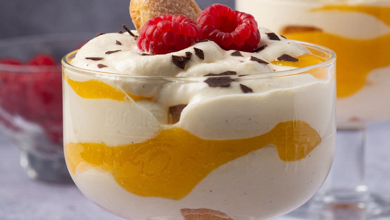 Layered cream dessert with raspberries in glass