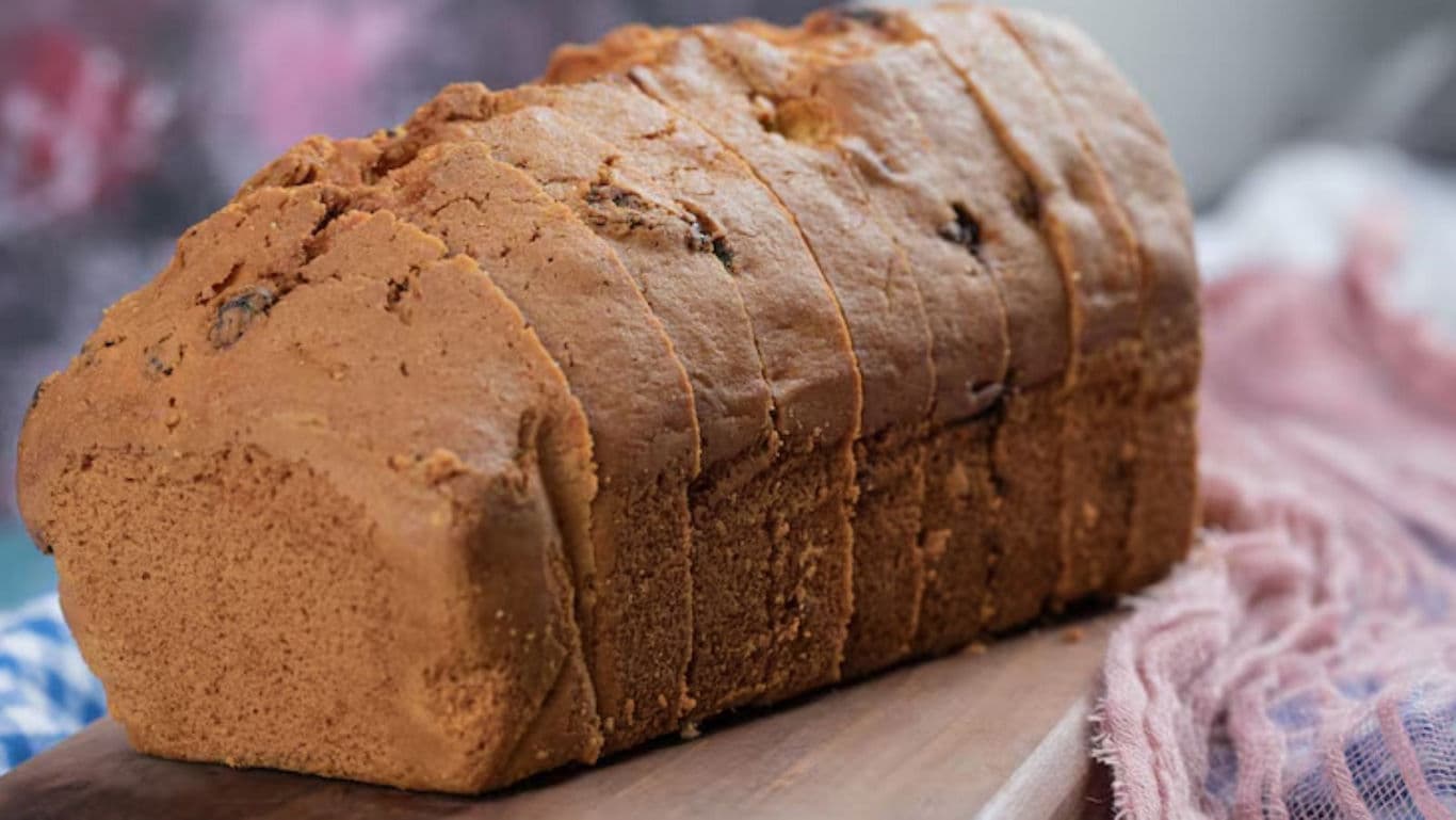 Sliced loaf of raisin bread on wooden board