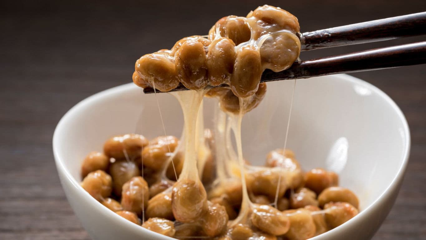 Chopsticks lifting sticky fermented soybeans from bowl