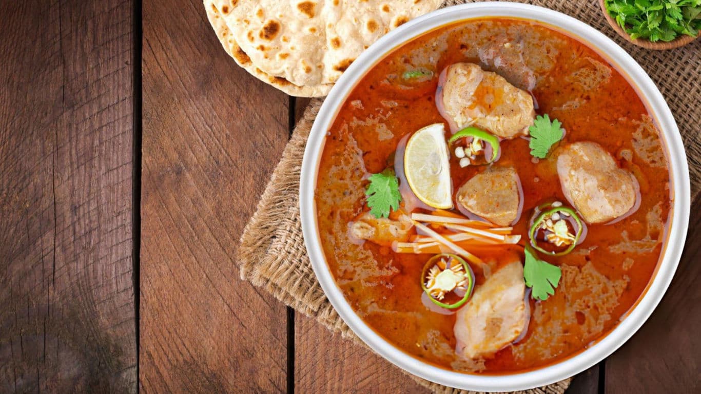 Spicy curry with bread on wooden table