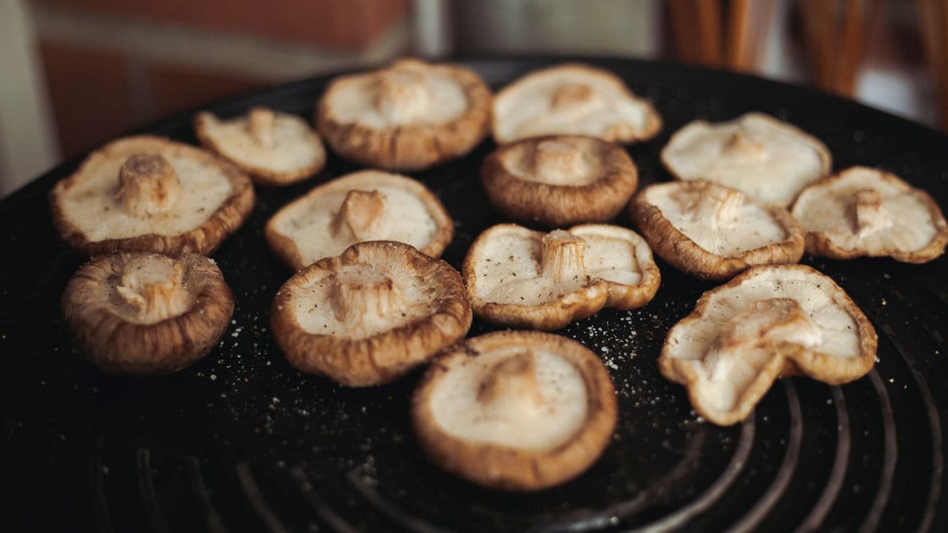 Fresh mushrooms cooking on grill surface