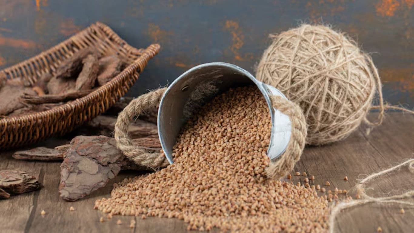 Buckwheat grains spilling from metal pail on wood