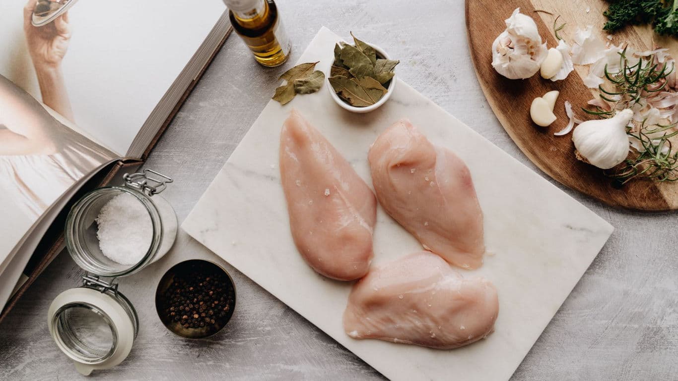 Raw chicken breasts with herbs and cookbook
