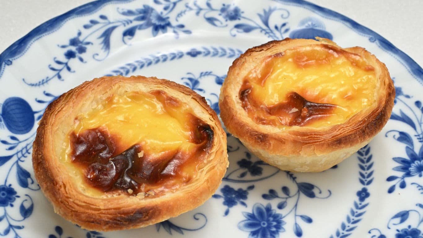 Two custard tarts on decorative plate