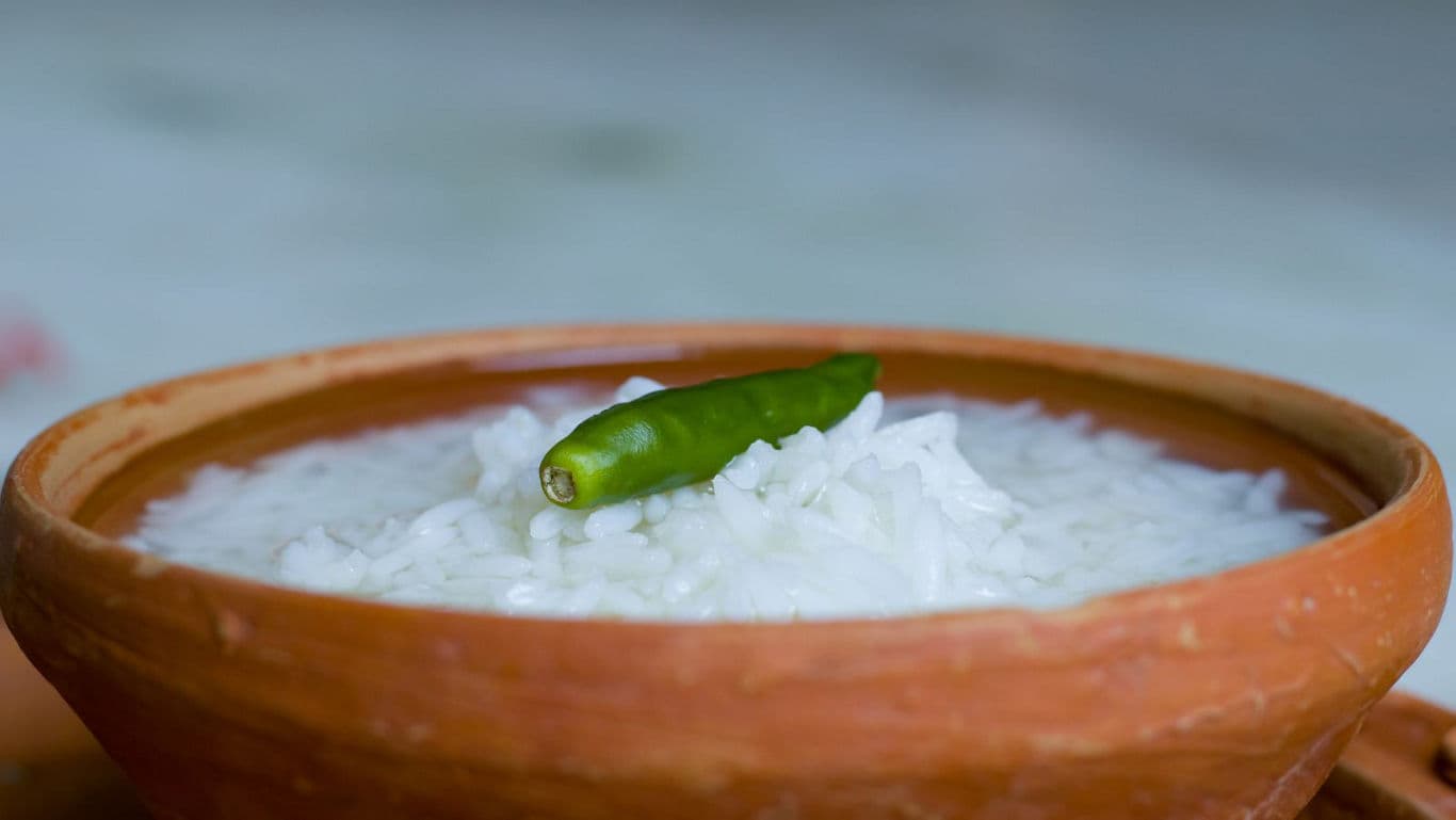 Clay bowl of rice porridge with green chili garnish