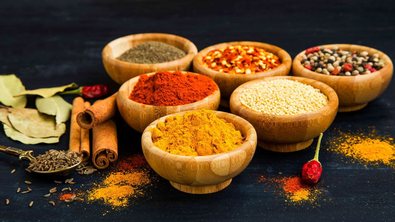 Assorted spices in wooden bowls on dark table