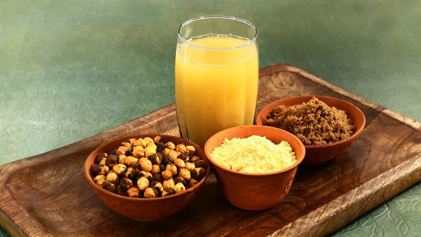 Glass of yellow juice with assorted snacks on tray