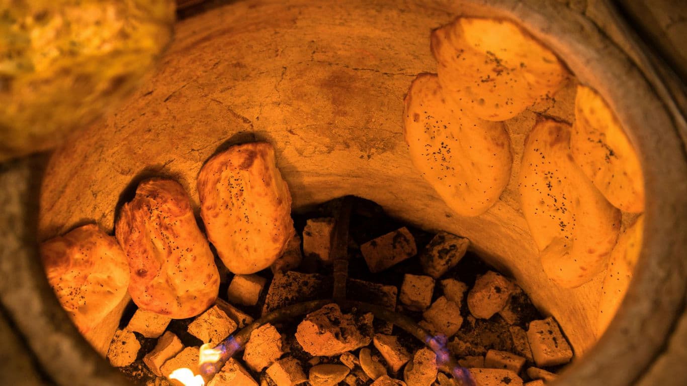 Traditional flatbreads baking inside clay tandoor