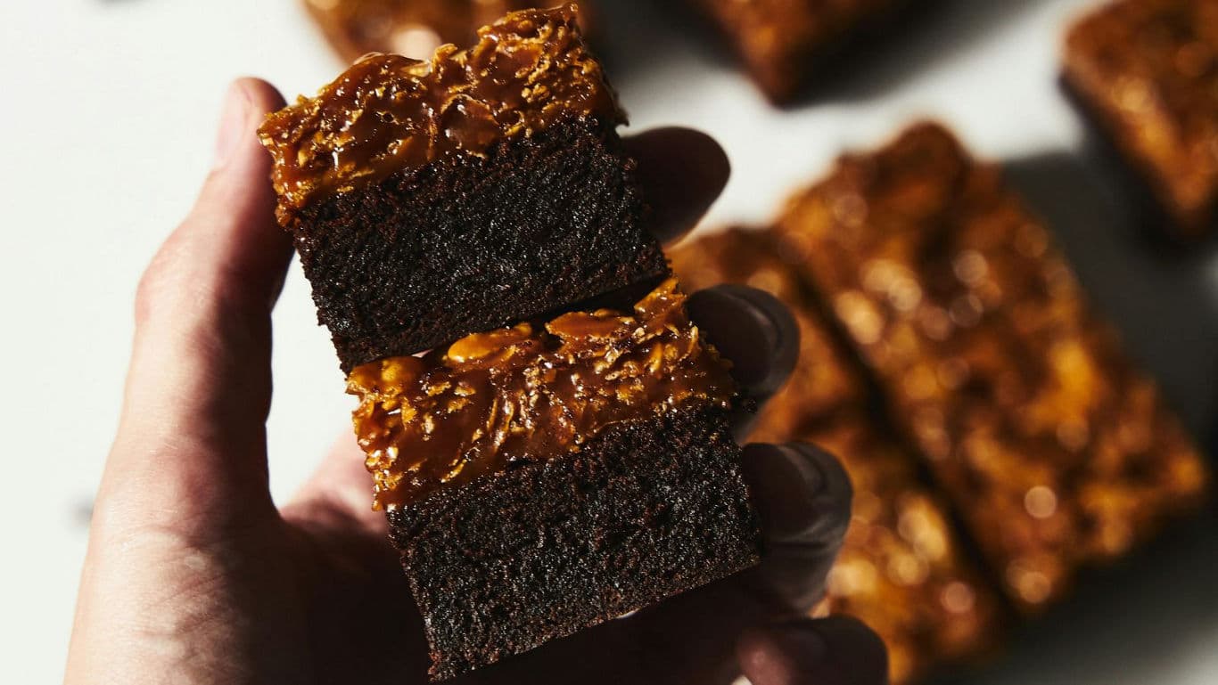 Hand Holding Two Caramel Chocolate Brownie Squares