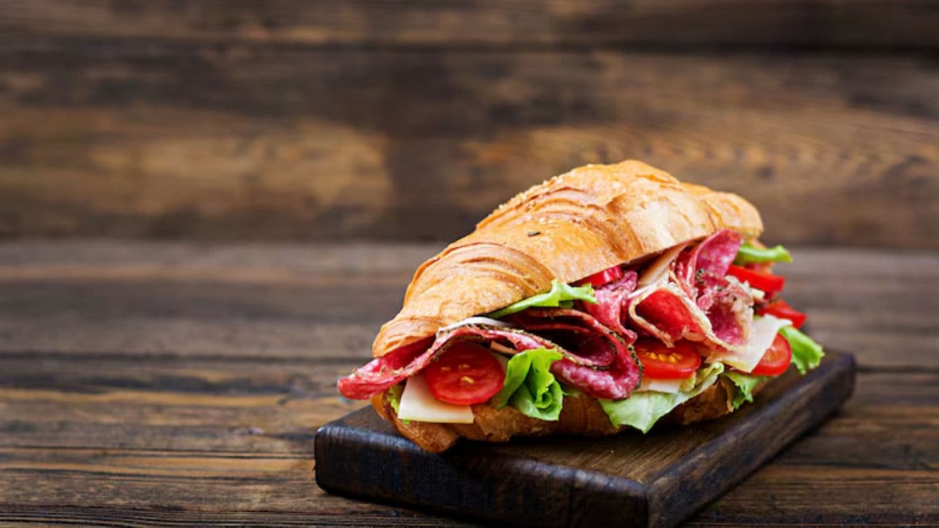 Croissant sandwich with salami, cheese, and vegetables
