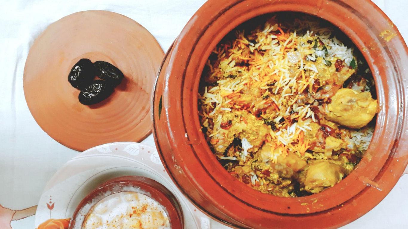 Aromatic Eid biryani served in a clay pot bowl with mint and fried onions on top.