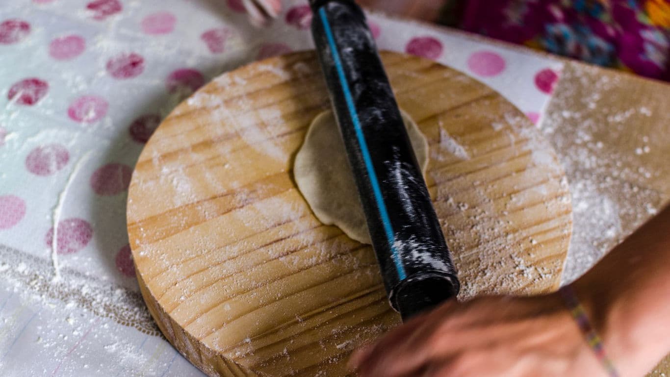 Rolling dough on wooden board with rolling pin