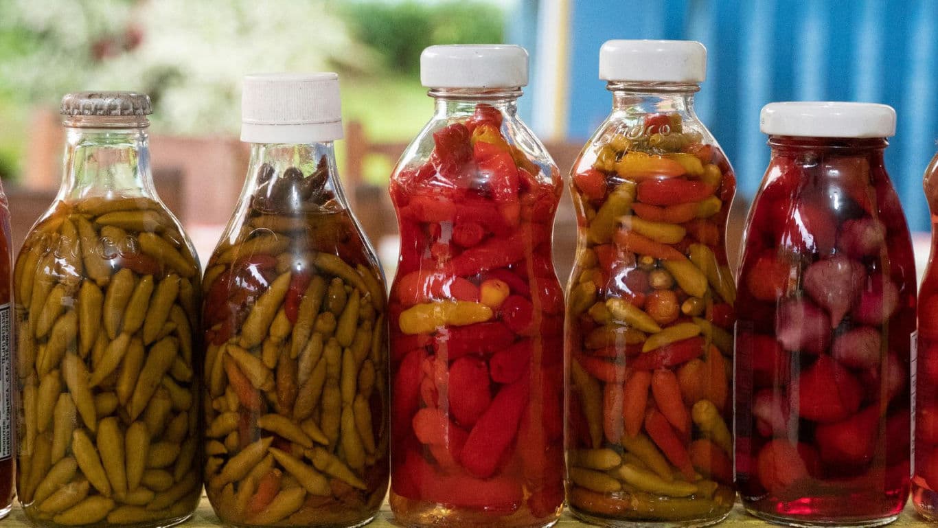 Assorted pickled peppers in glass bottles on display