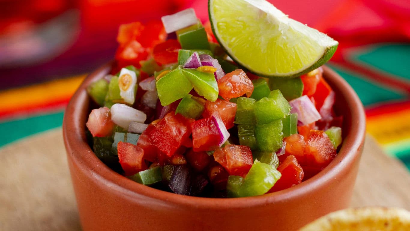 Fresh salsa in terracotta bowl with lime