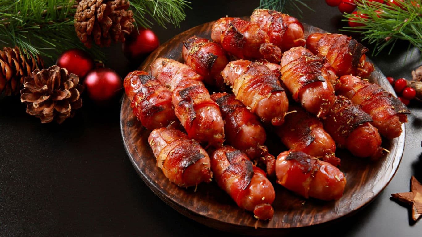 Festive bacon-wrapped sausages on wooden plate