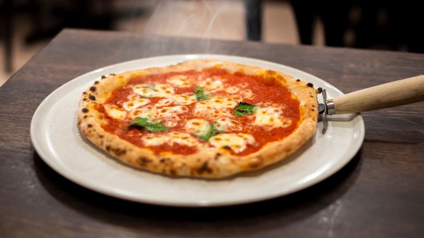 Freshly baked margherita pizza on wooden table