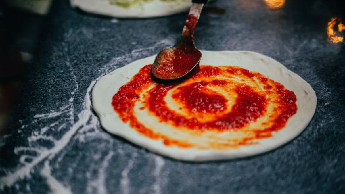 Spreading sauce on pizza base