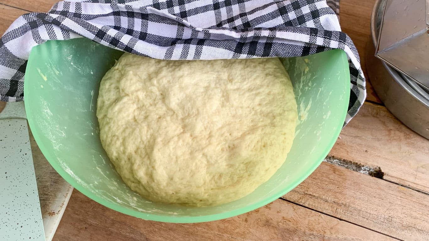 Risen bread dough in green mixing bowl