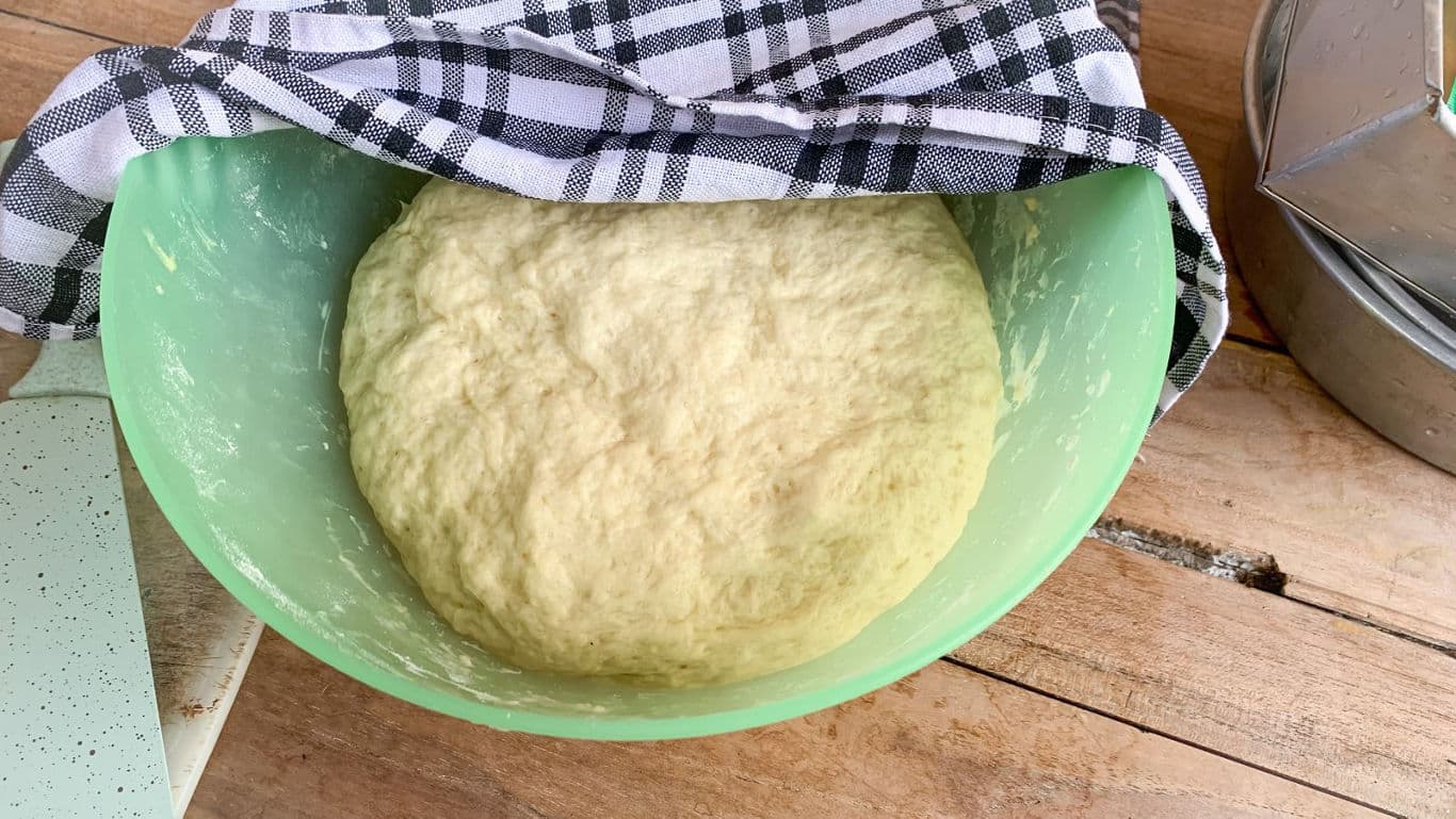 Risen bread dough resting in green bowl