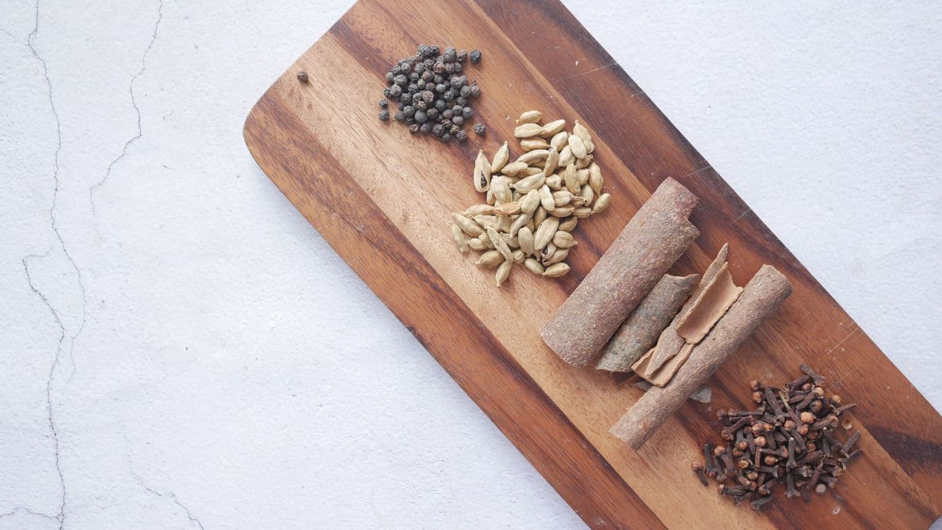 Assorted whole spices on wooden board