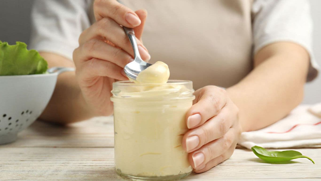Woman scooping creamy spread from jar