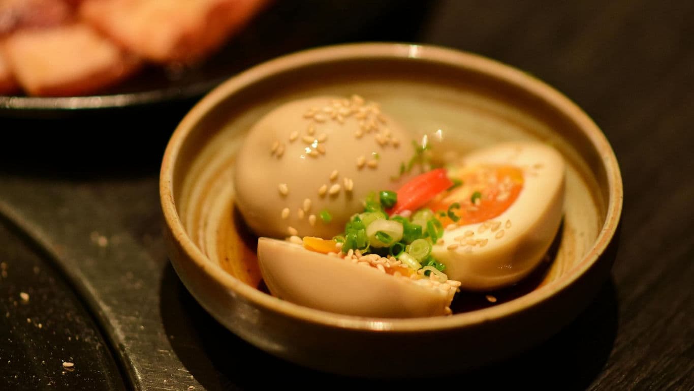 Soft-boiled seasoned eggs with sesame garnish