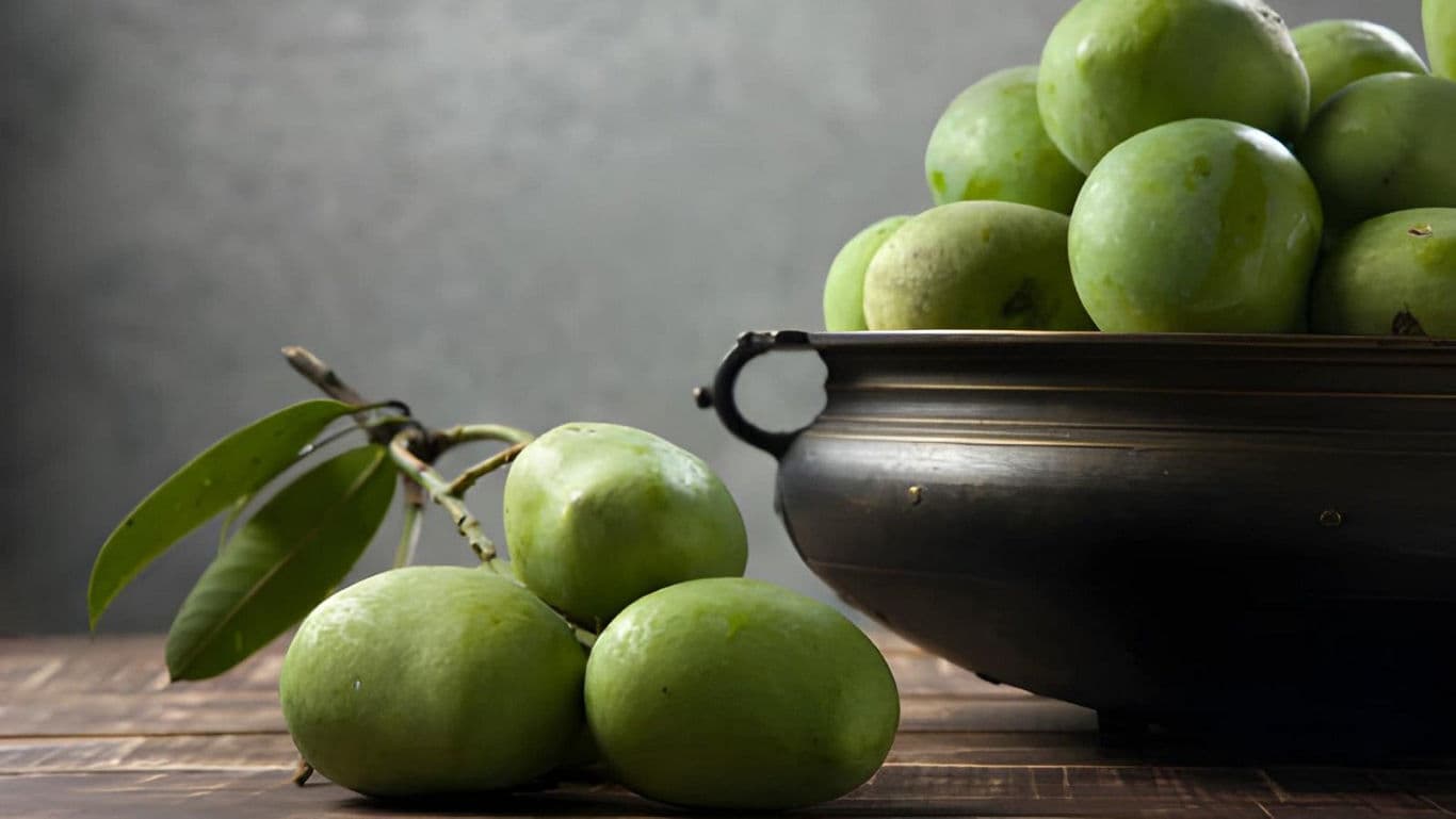 Fresh green mangoes in a rustic metal bowl