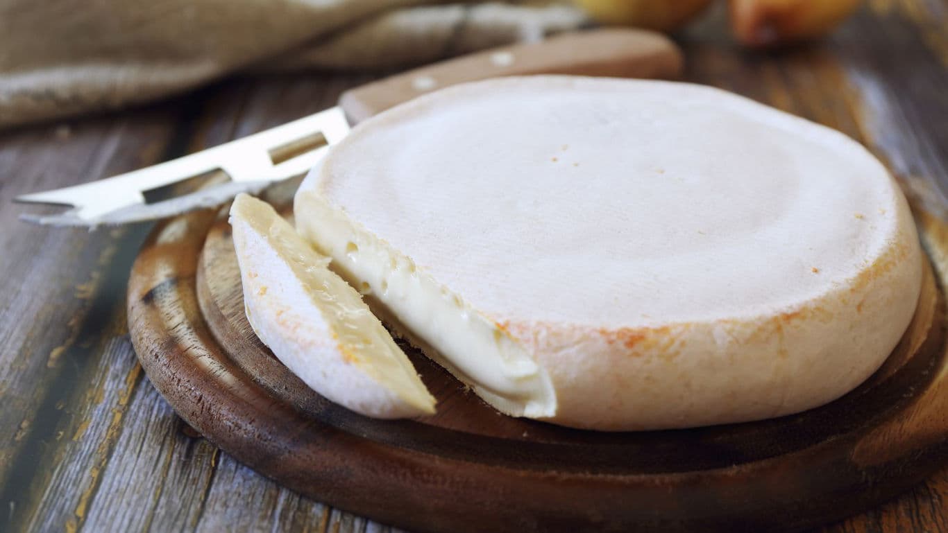 Soft round cheese wheel on wooden board