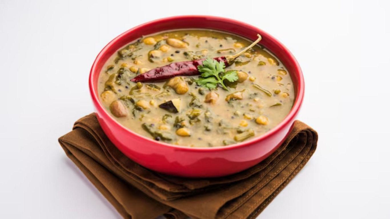Red bowl of lentil curry with chili garnish