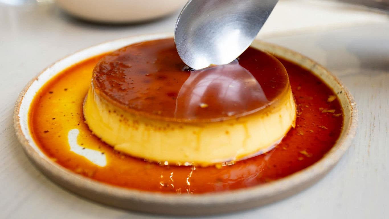 Spoon scooping creamy caramel flan dessert
