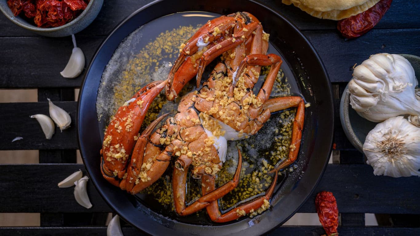 Cooked crab with garlic and spices in black bowl