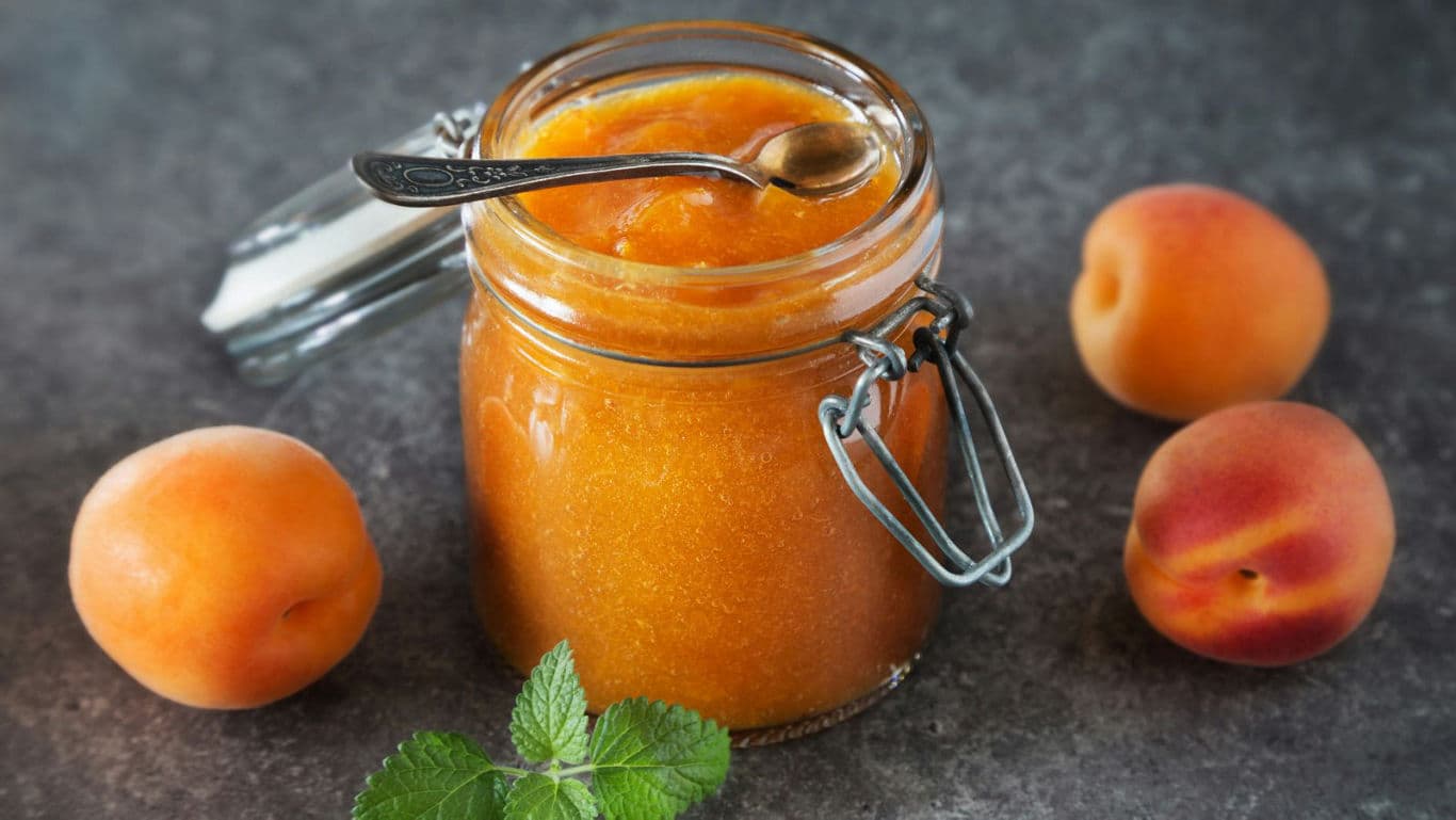 Glass jar of apricot jam with spoon