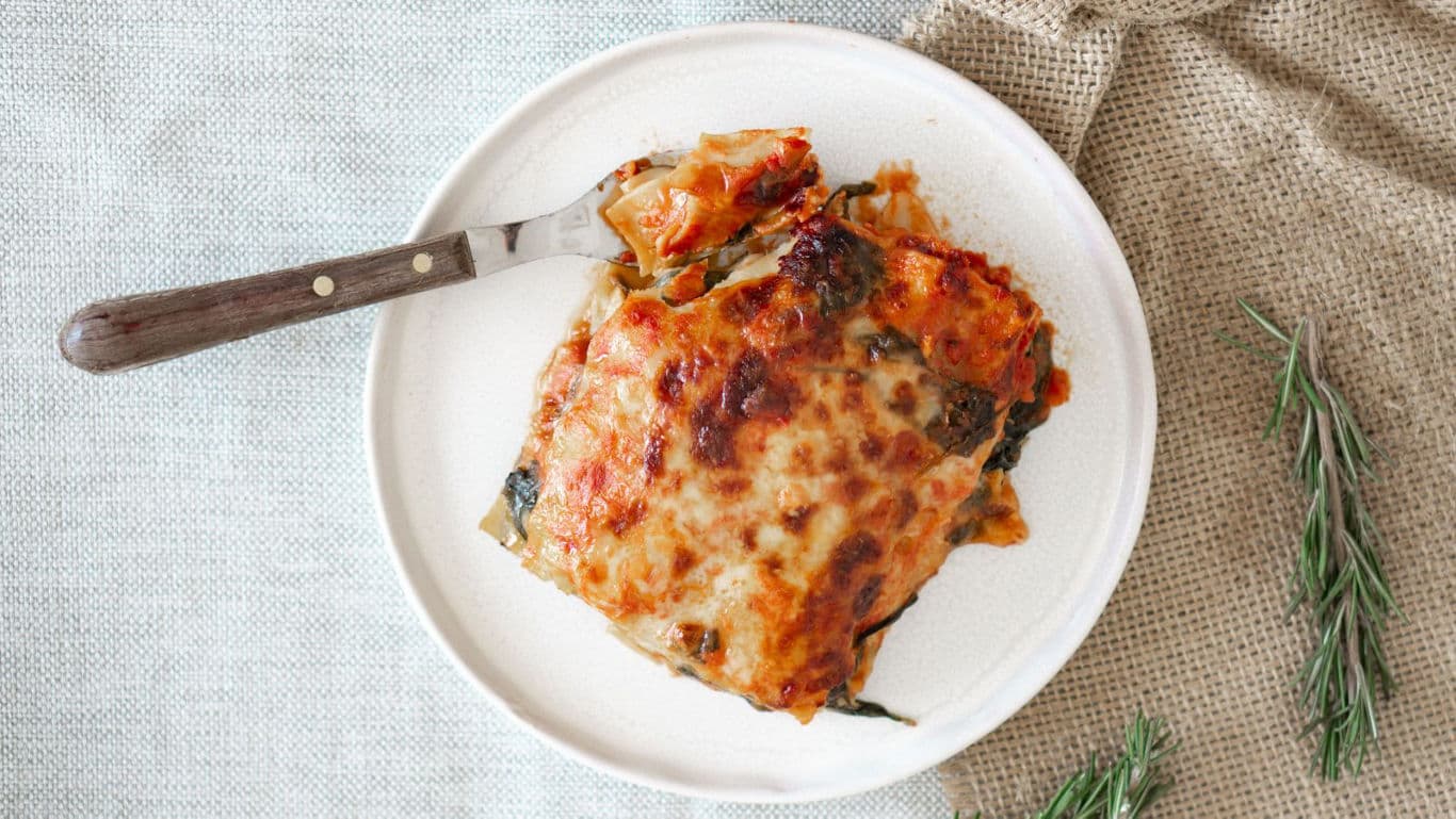Baked lasagna slice on rustic white plate