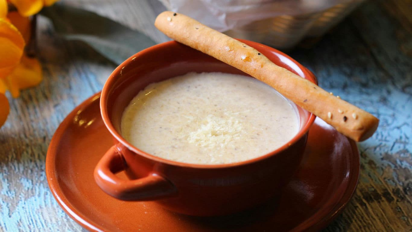 Creamy soup in rustic terracotta bowl