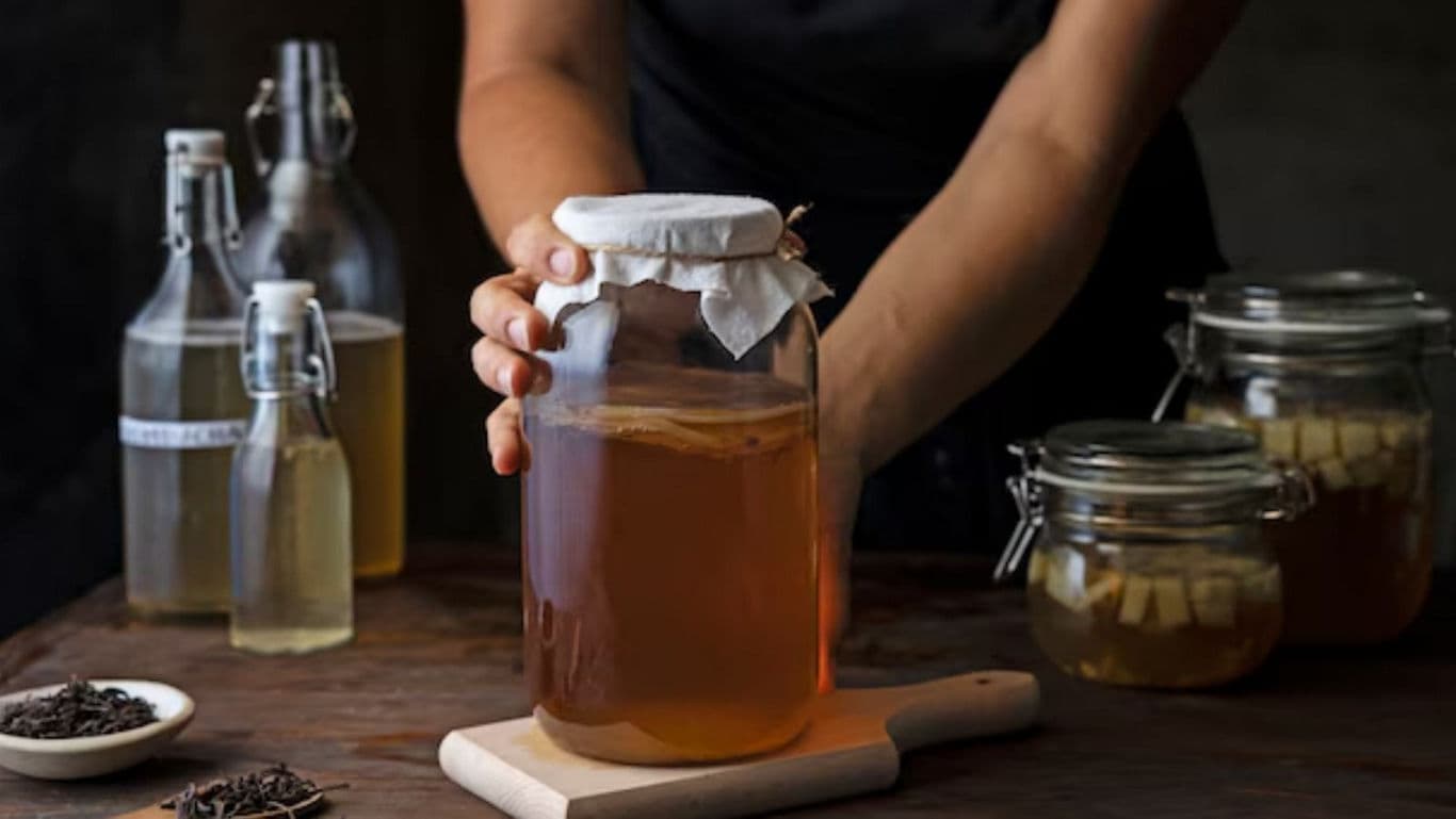 Person preparing homemade kombucha in glass jars