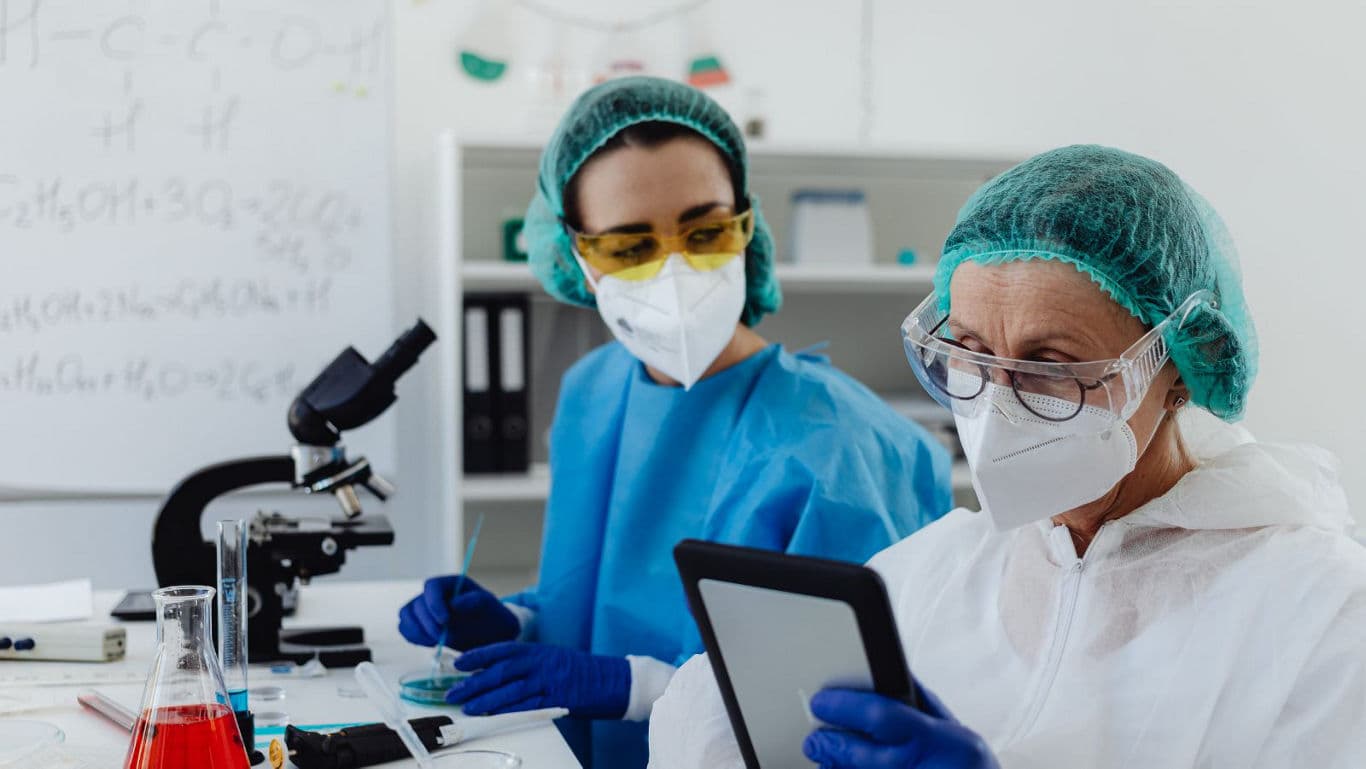 Scientists in laboratory using tablet and microscope