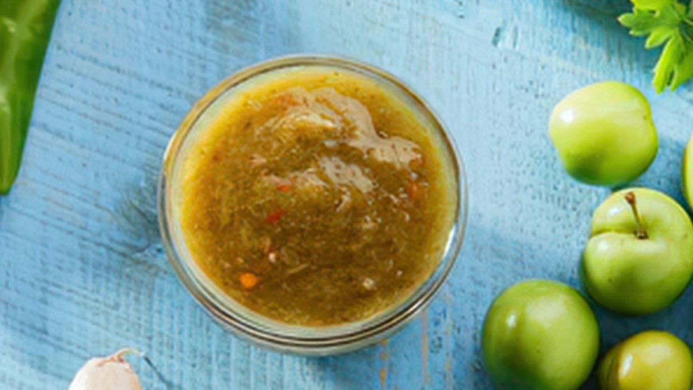 Glass bowl of green salsa with tomatillos
