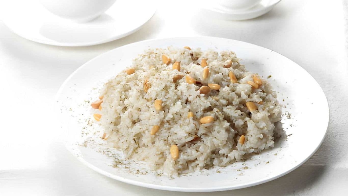 White rice pilaf with pine nuts on white plate