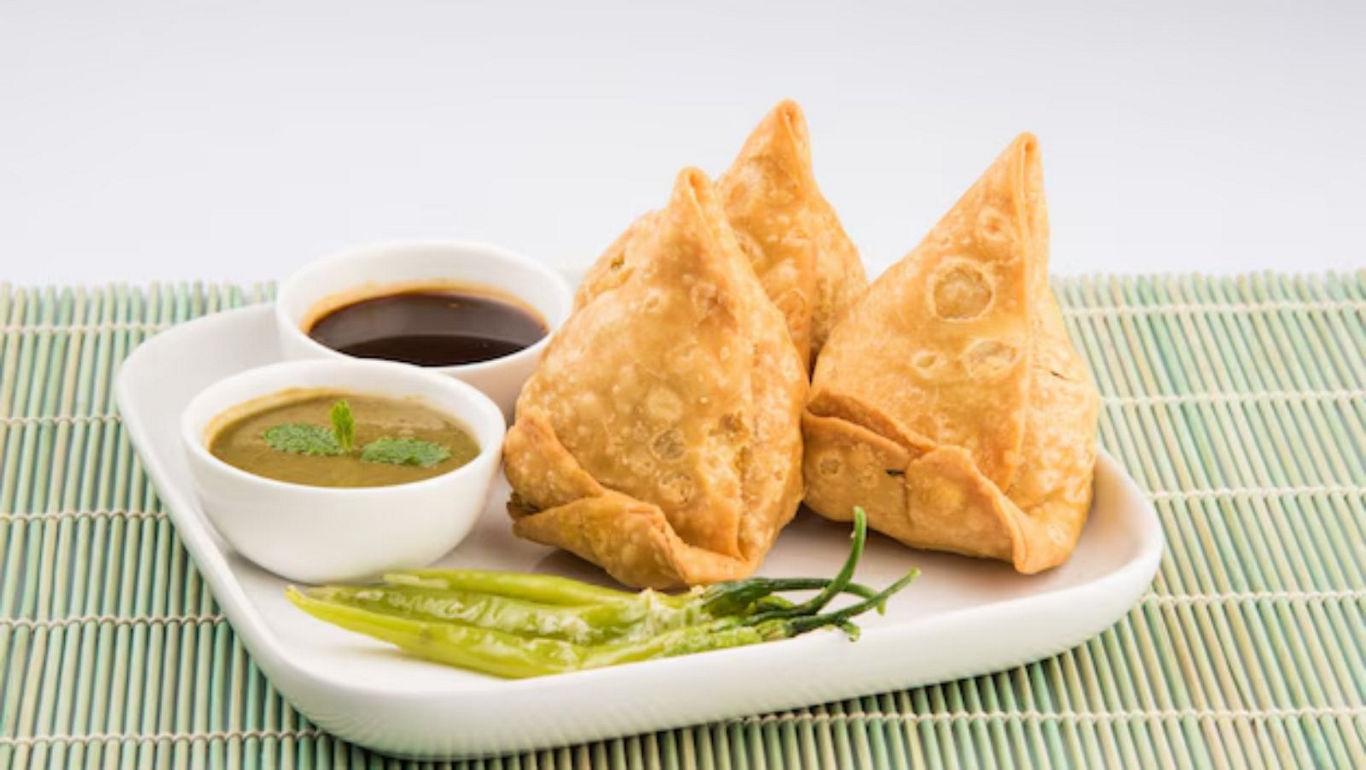 Crispy samosas with chutneys on plate
