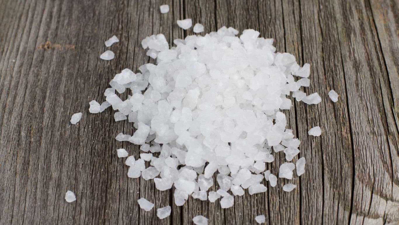 Coarse sea salt crystals on rustic wooden surface
