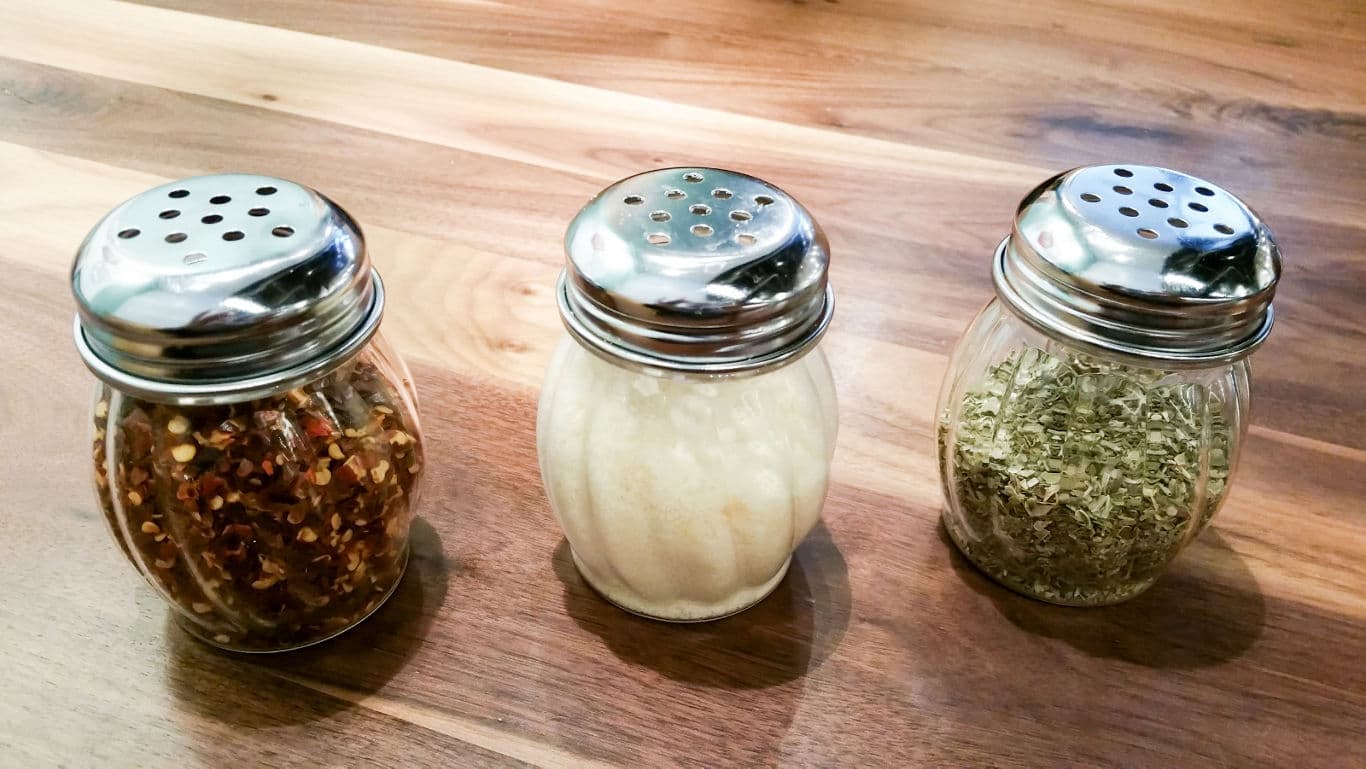 Three spice shakers on wooden table