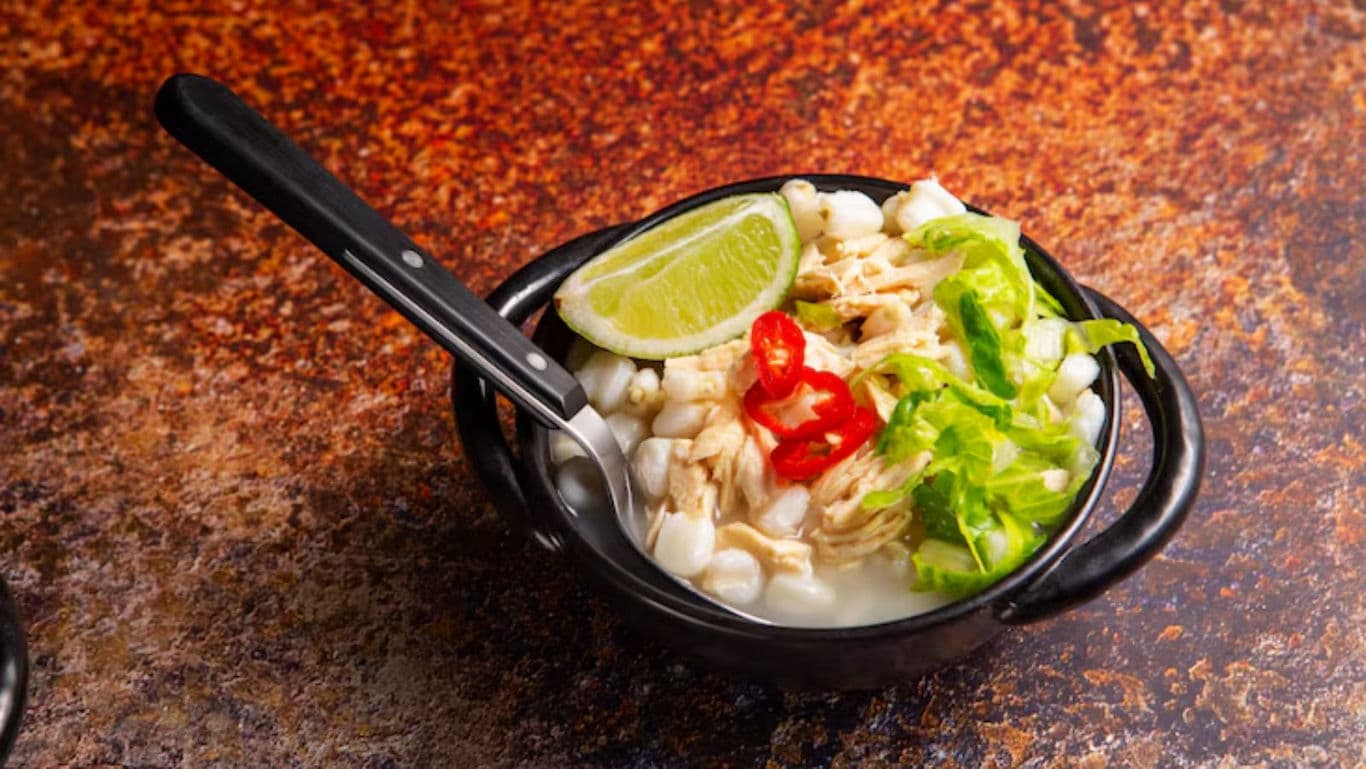 Bowl of chicken hominy soup with lime