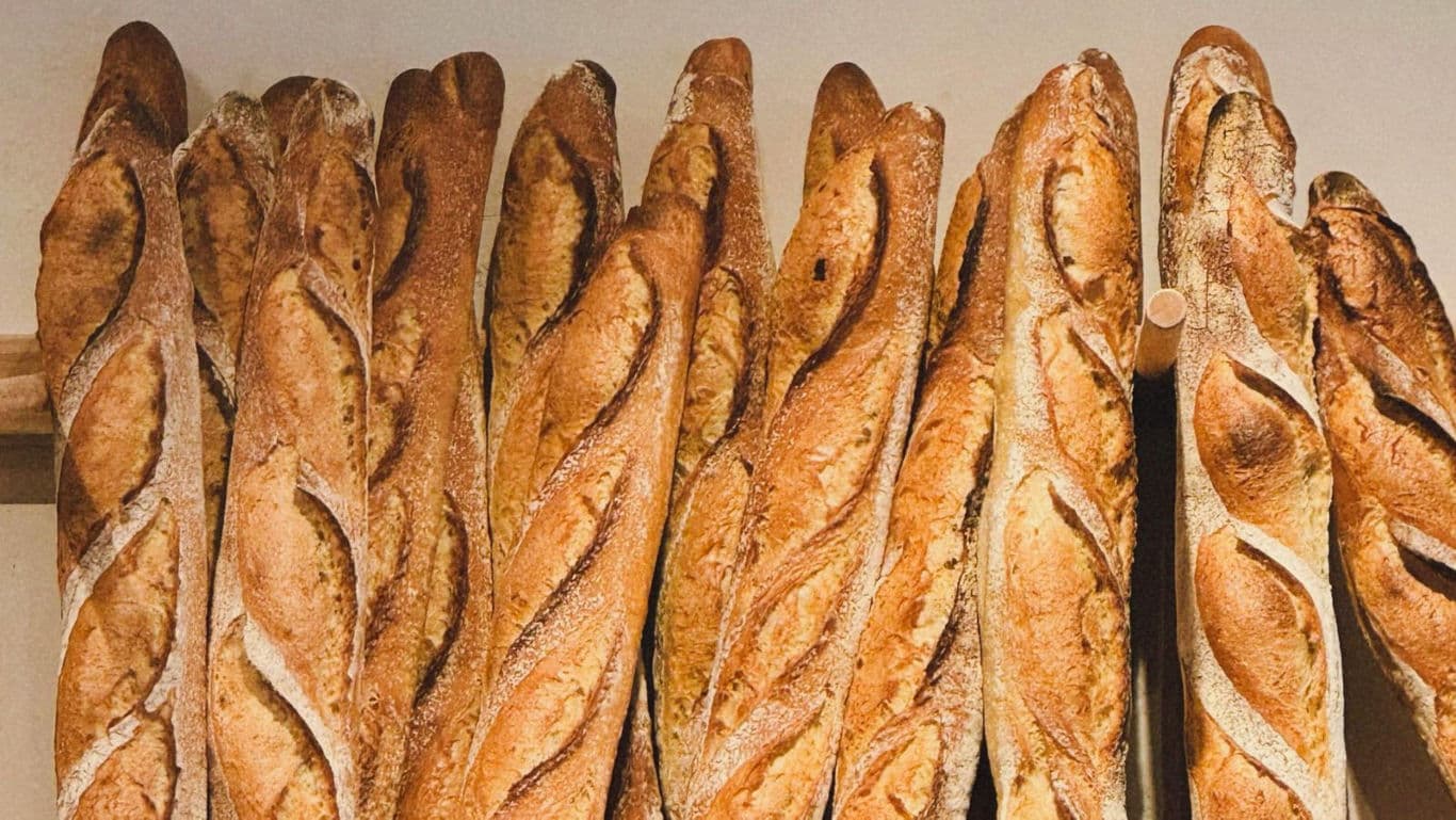Fresh crusty baguettes stacked in bakery rack