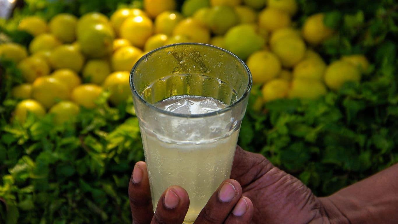 Hand Holding Glass of Fresh Lemon Juice Outdoors
