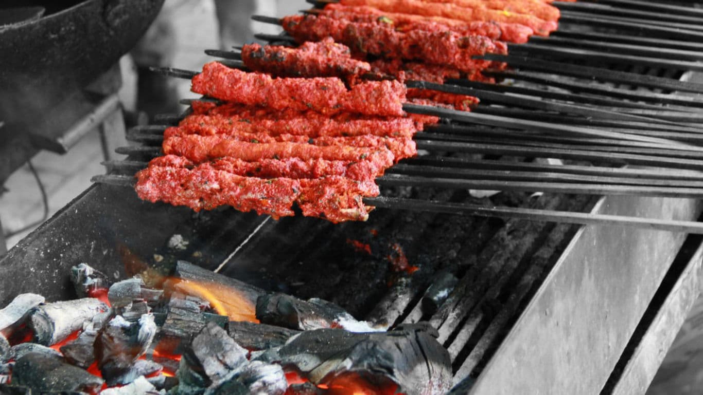 Spiced meat skewers grilling over hot charcoal fire